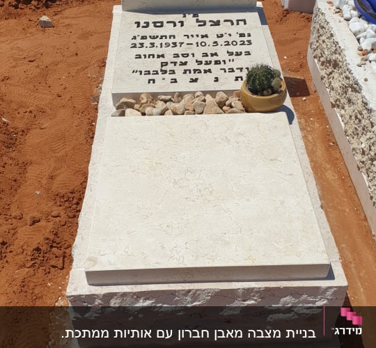 מצבה עם כיתוב בעברית ואבנים קטנות